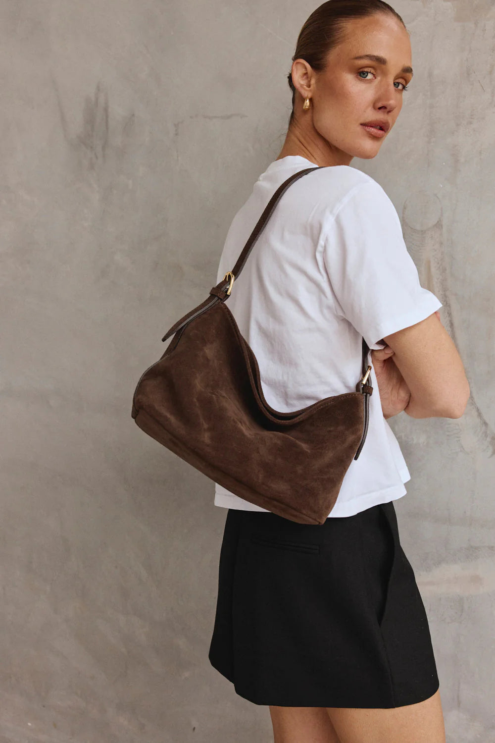 Woman carrying a brown leather handbag against a neutral background