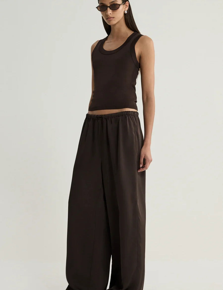 Model wearing the Elka Collective Mina Satin Pant in chocolate brown, featuring a relaxed wide-leg silhouette and elastic waistband, styled with a matching tank top. or hayes knit top 
Crafted from luxuriously soft, double-faced recycled Japanese satin, its flowing wide-leg silhouette brings together comfort and quiet sophistication.