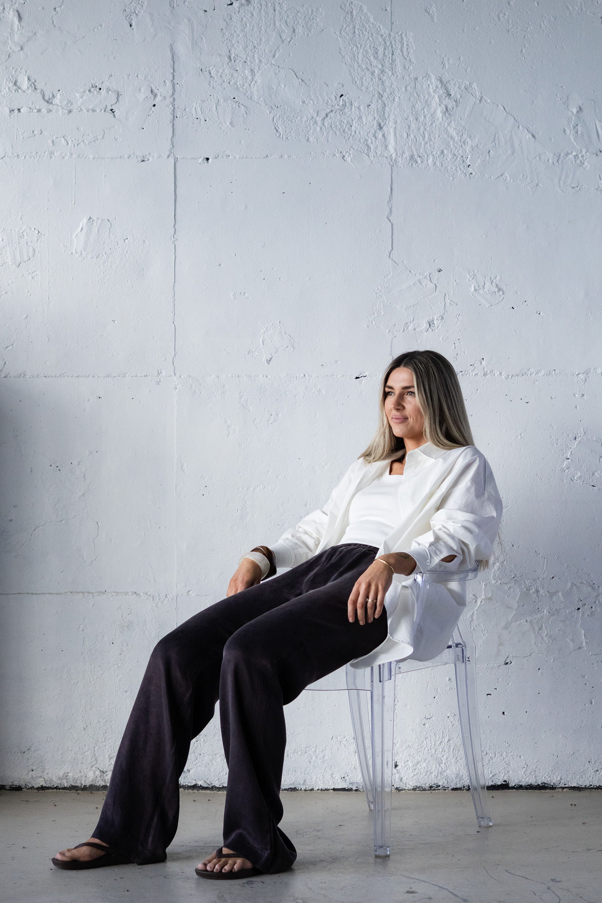 Woman sitting on a chair against a white wall